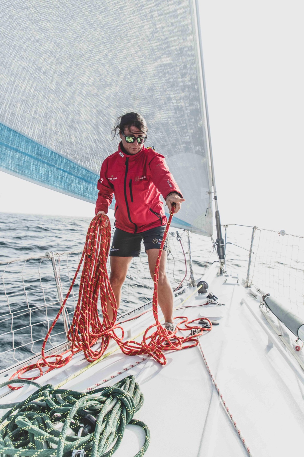 A female sailor working lines on deck under sail